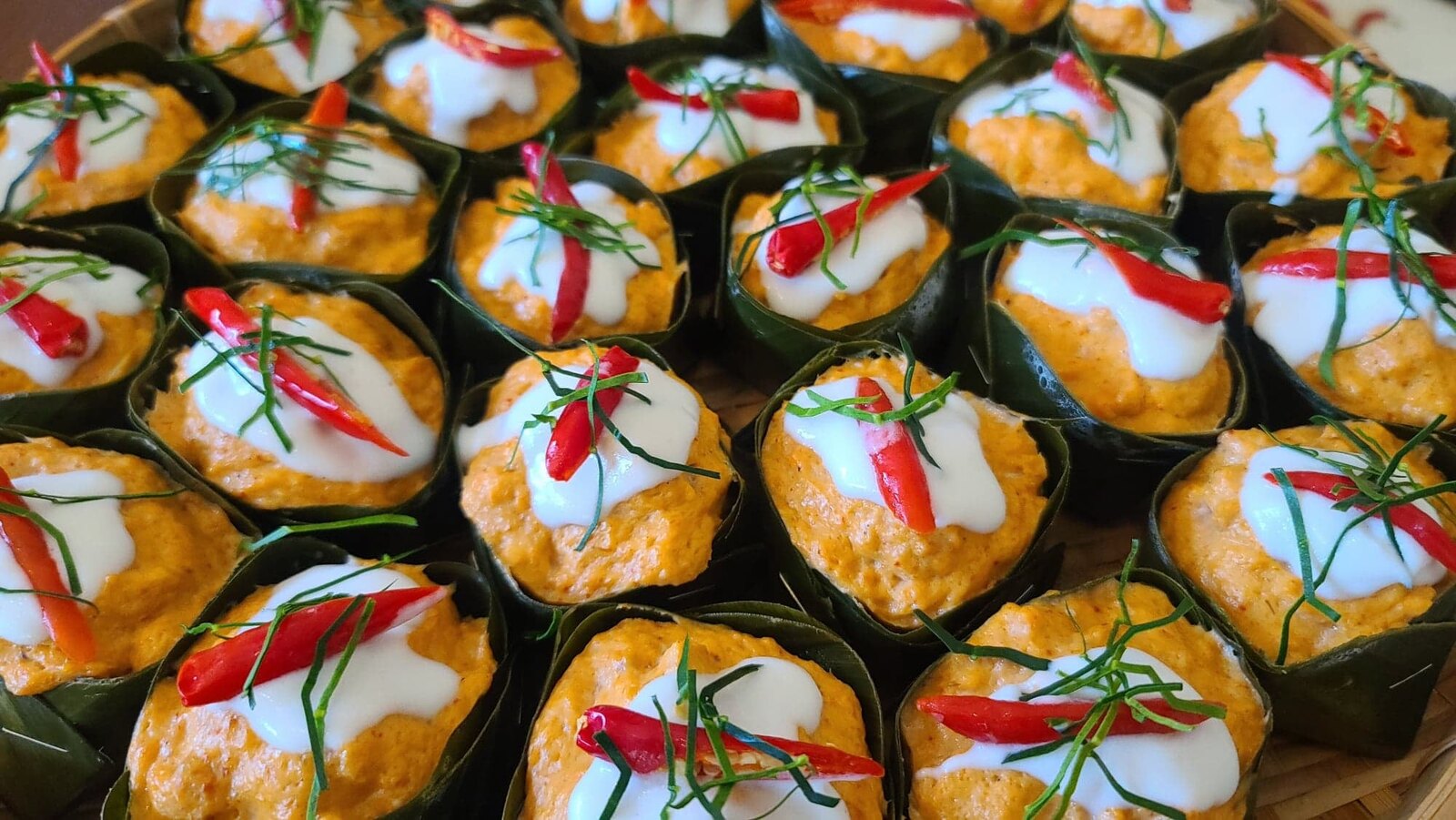 Hor mok — steamed red curry custard set in banana-leaf cups, topped with coconut cream, chili and kaffir lime.